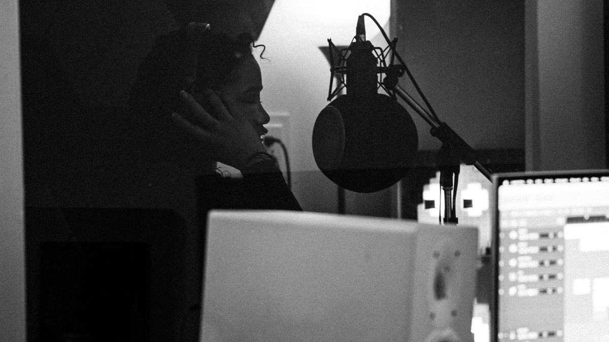 Human vocalist recording in a studio as AI music raises questions about synthetic voices