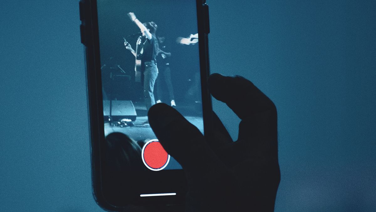 Live music audience recording a performance on a smartphone during the streaming era