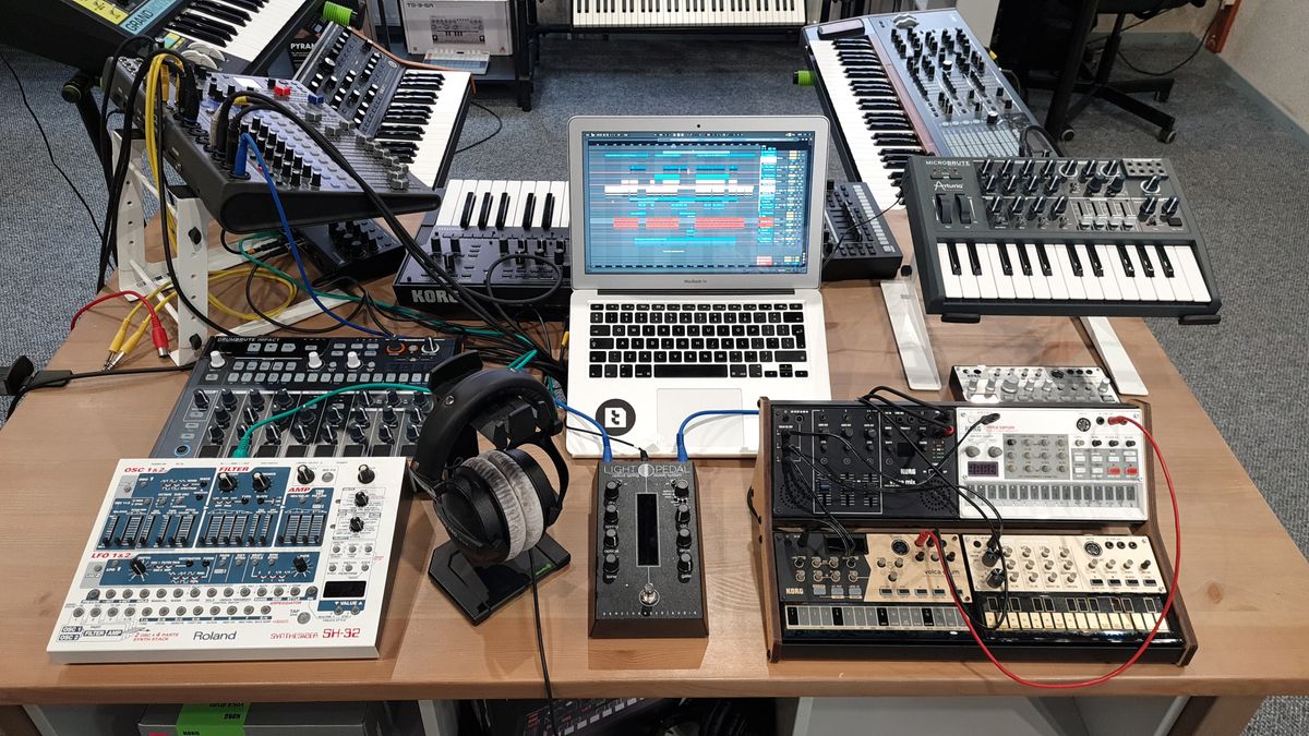 Suno AI music production studio with synthesizers and laptop