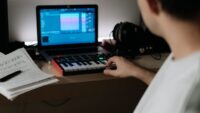 Creator using a synthesizer and laptop for digital music production